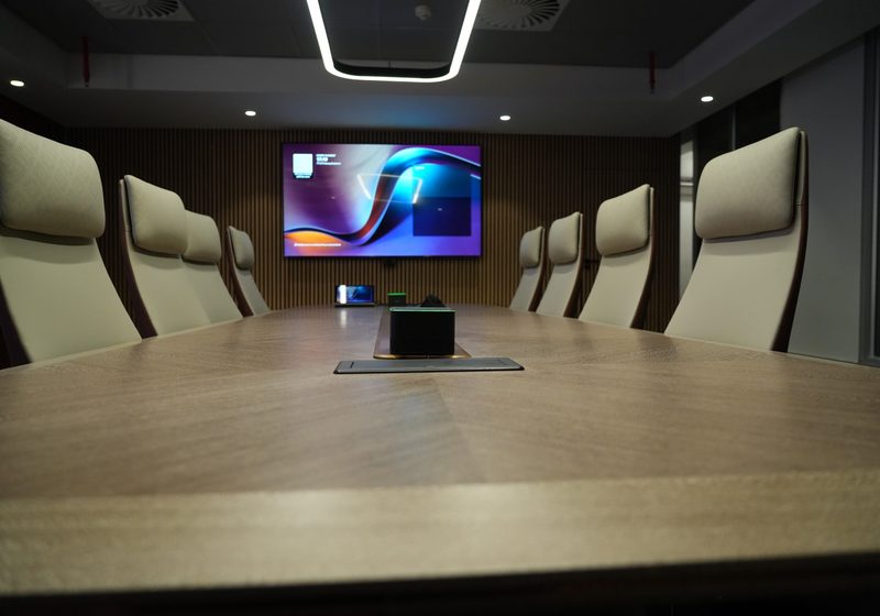 Executive boardroom table with integrated collaboration technology and display.