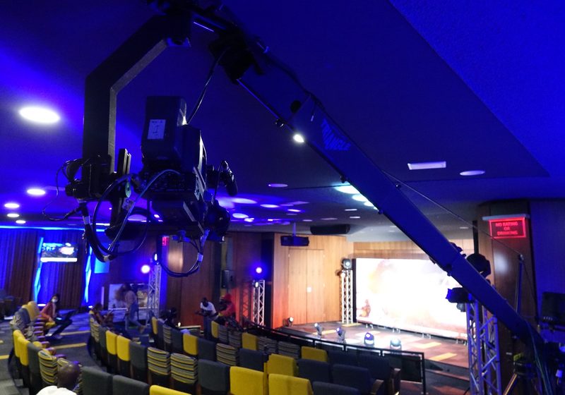 Camera jib and professional camera positioned over a lit event room.