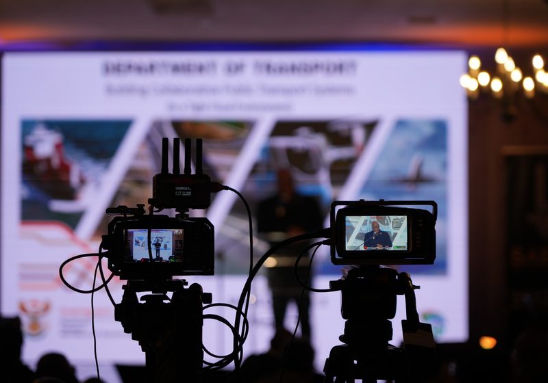 Innovar camera operator filming a live event with audience and stage in the background.