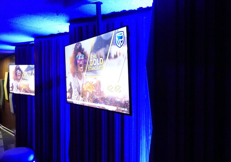 Venue display screens with blue uplighting in a meeting environment.