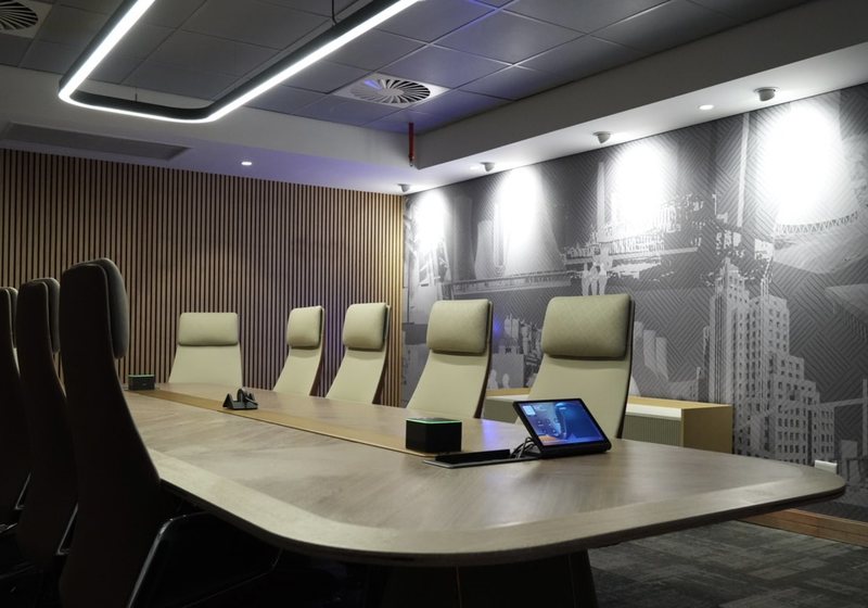 Boardroom table with a touch panel, microphone hub and a printed feature wall behind
