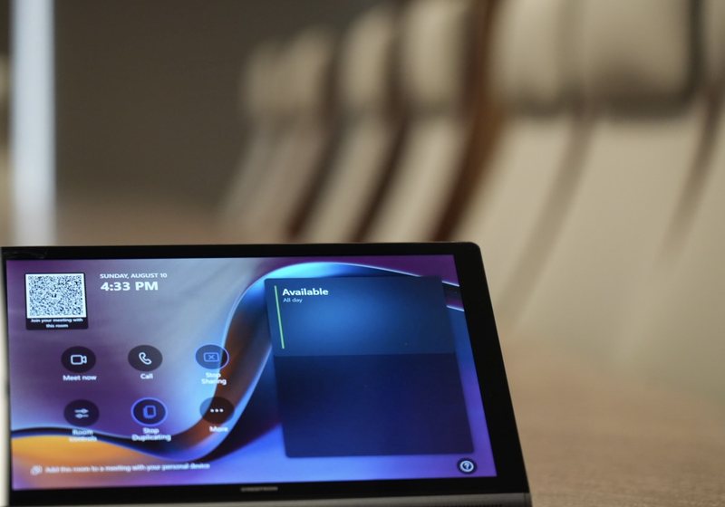 Close-up of a boardroom touch control panel on the table with chairs blurred behind