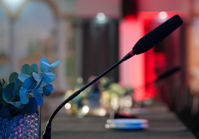 Gooseneck delegate microphone with a foam windscreen beside a floral centrepiece on a conference table