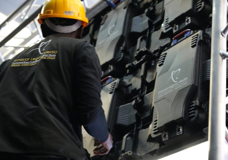 Technician working behind an LED screen wall during installation.