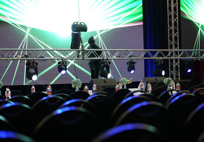 Technicians setting up an LED screen wall inside a truss structure.