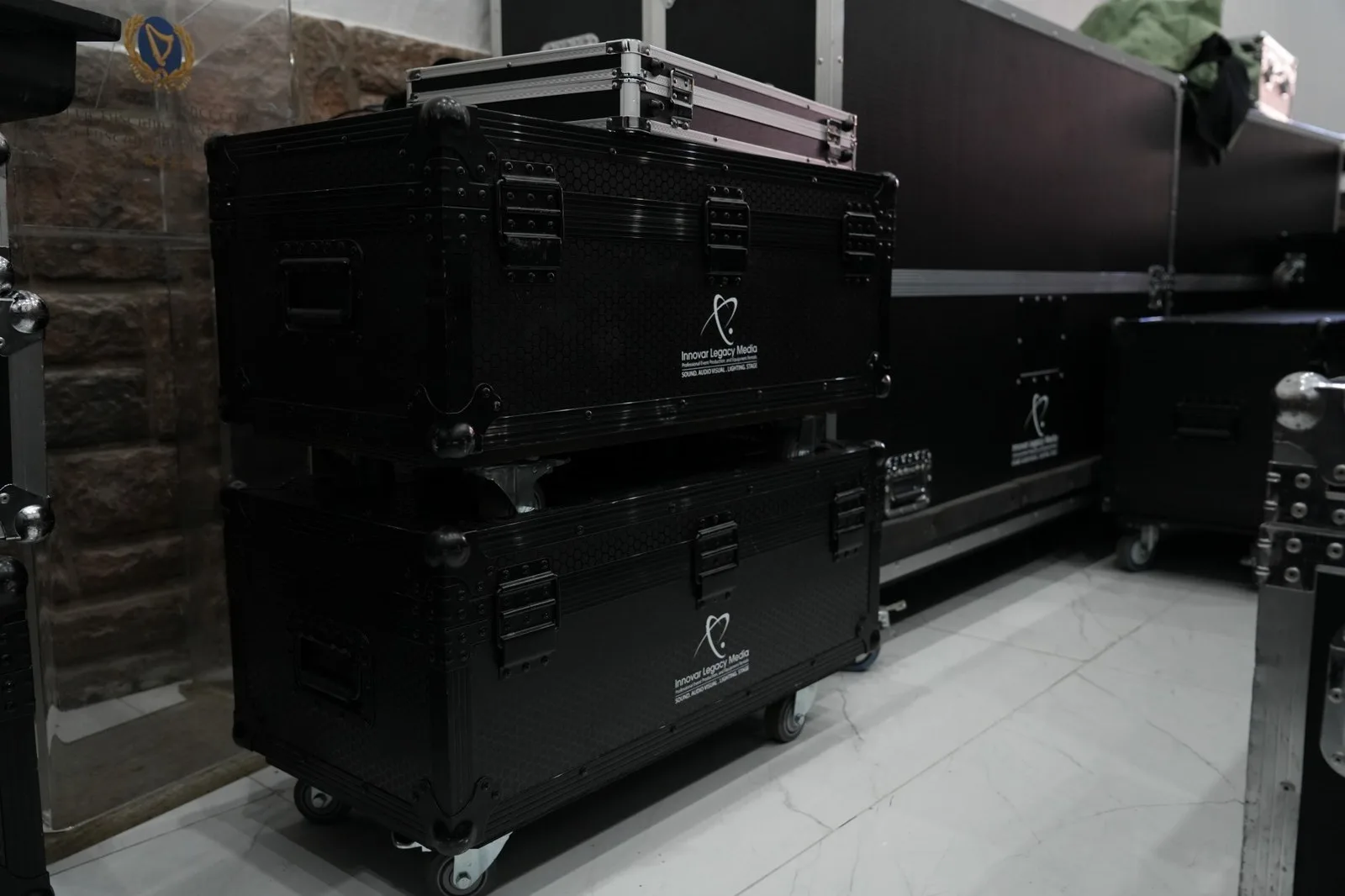 Two stacked black Innovar Legacy Media flight cases on castors beside a larger case